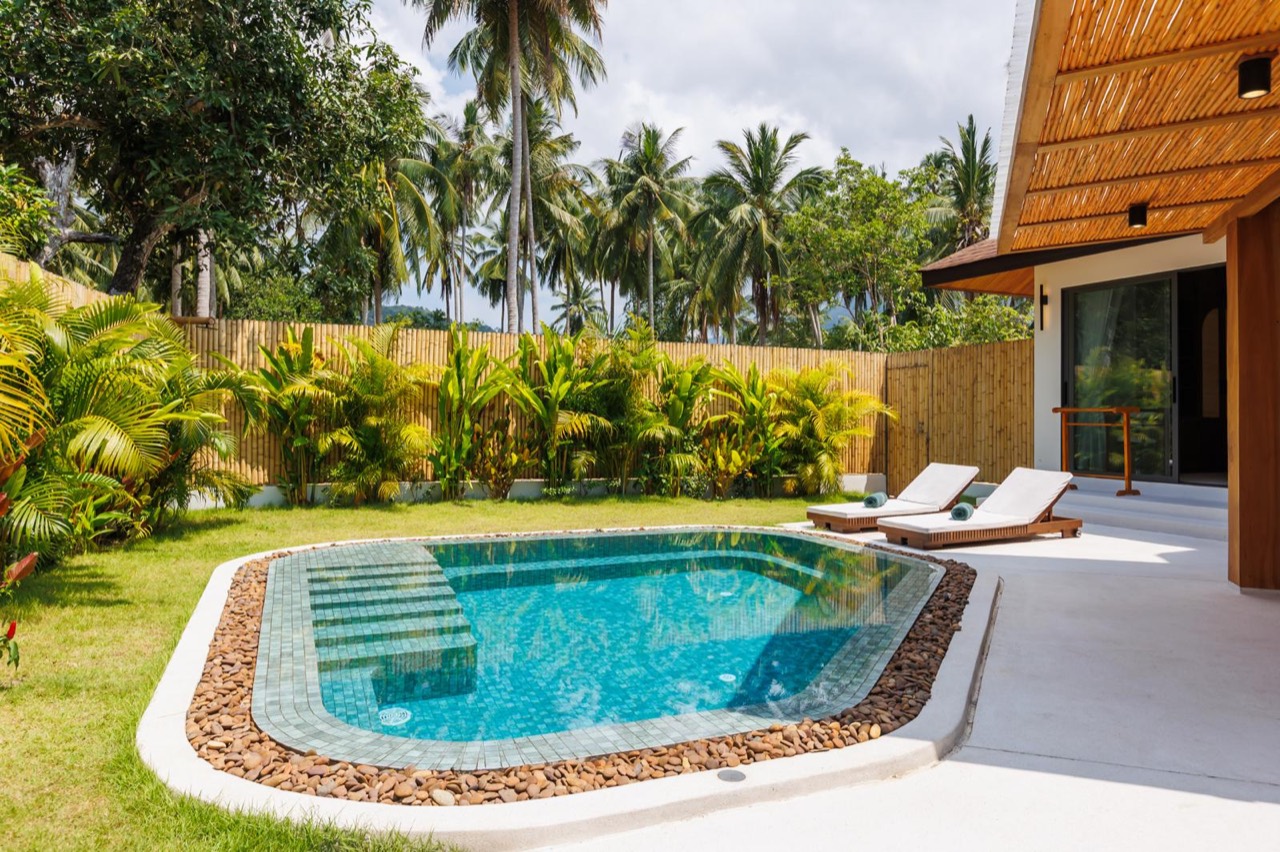 Private turquoise swimming pool surrounded by palms and sun loungers